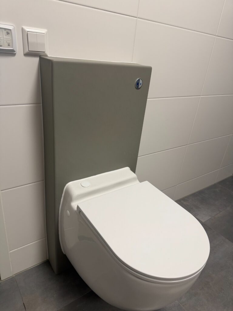 Geplaatst hangtoilet met grijze achterwand en wit betegelde muren