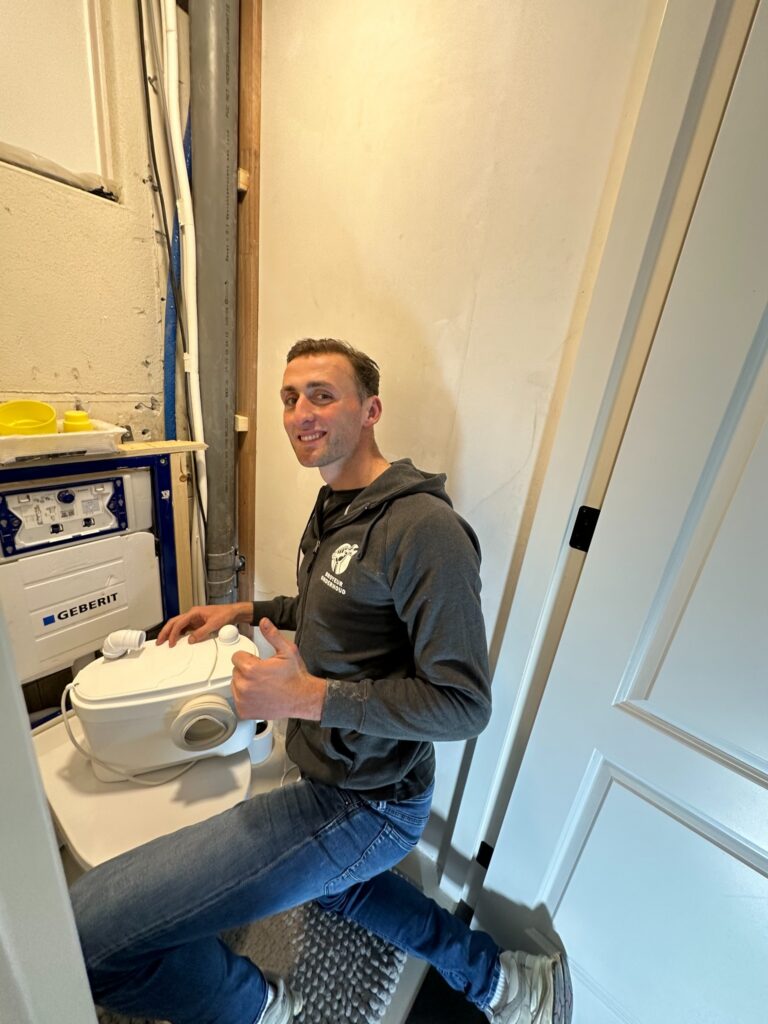 Monteur met een broyeur bij de inbouwinstallatie van een toilet
