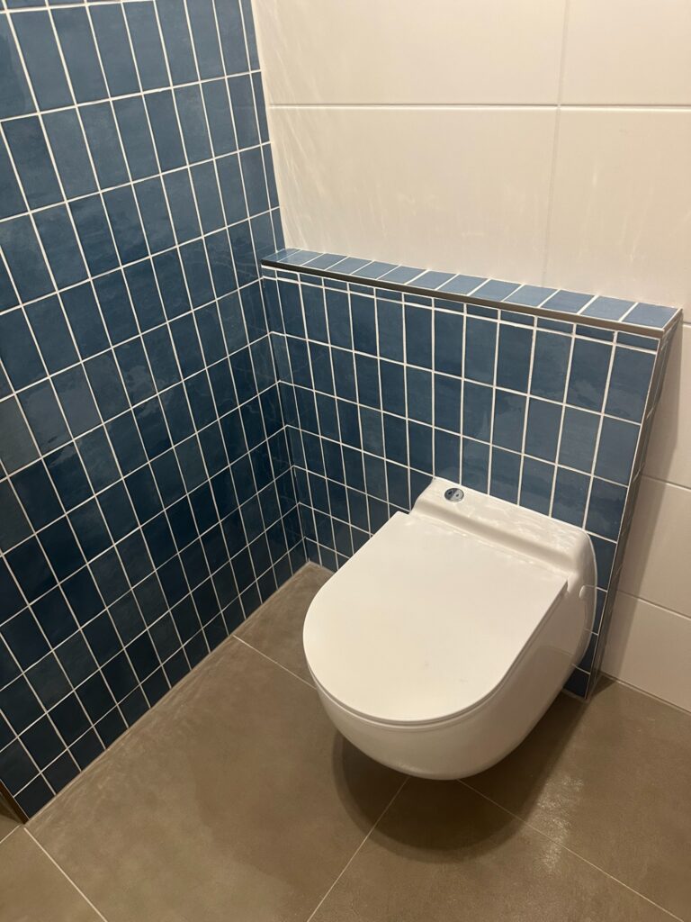 Geplaatst wit hangtoilet in een toiletruimte met blauwe wandtegels